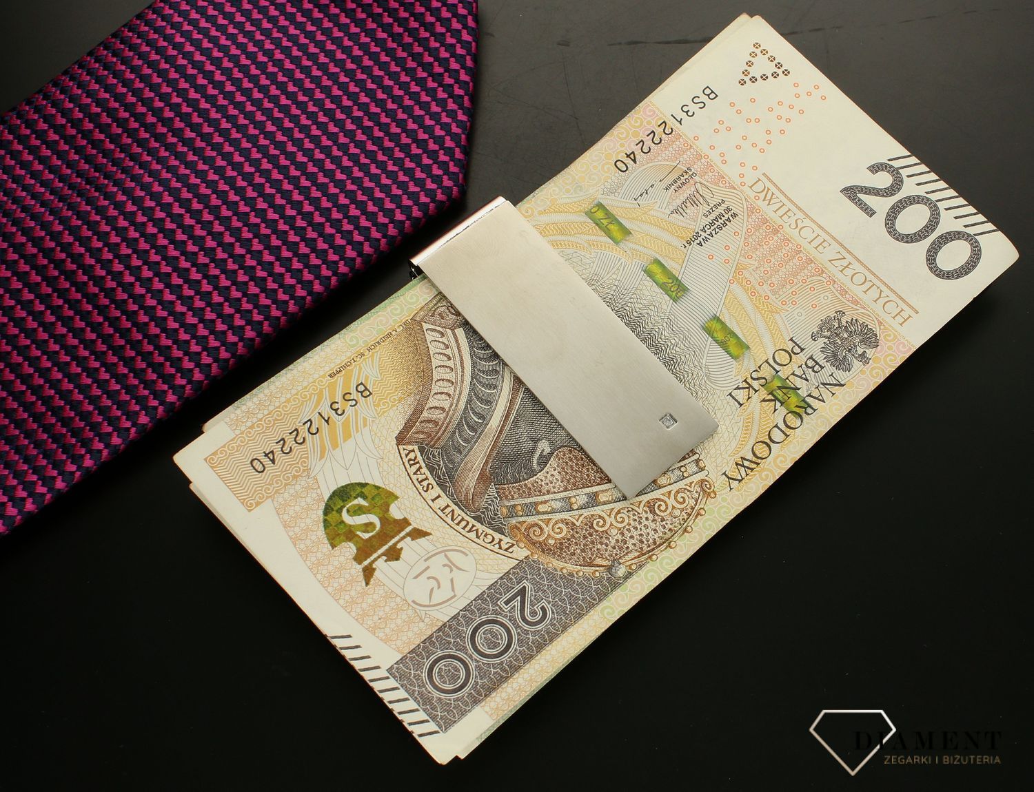 Klips do banknotów Nomination z Diamentem 028310 008. Oryginalny klips do banknotów wykonany ze stali szlachetnej pokryty metodą PVD w kolorze srebrnym. Elegancji dodaje jasny diament na najbardziej widocznym miejscu.webp